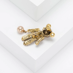 Détail du dos d'une broche ours dorée avec fermoir épingle et pendentif perle champagne