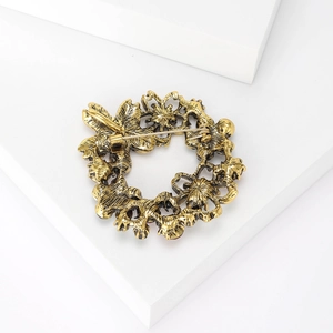 Detail of vintage gold wreath brooch with star patterns on a minimalist stand