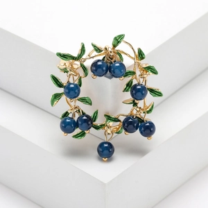 Elegante spilla a corona di bacche dorate con foglie di smalto verde e perline blu lucide