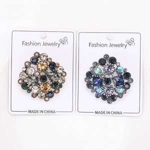 Detailed close-up of vintage rhinestone brooches in gold and blue on fashion display cards