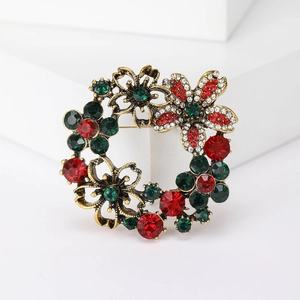 Detailed macro view of vintage gold wreath brooch with red and green crystals