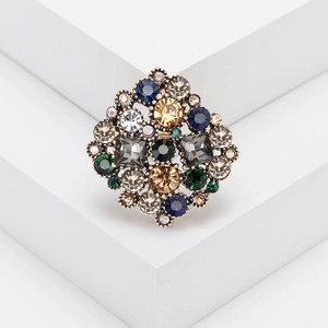 Vintage rhinestone brooch with colorful crystals on a geometric white platform