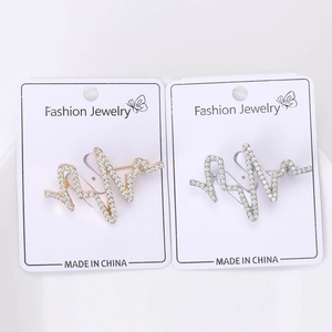 Détail macro de broches battement de cœur dorées et argentées serties de strass