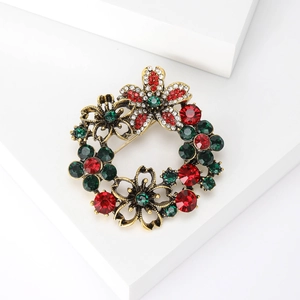 Macro detail of Christmas wreath brooch with red and green rhinestones on vintage gold metal