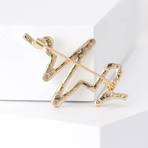 Élégante broche ECG dorée avec motif floral en relief sur un support minimaliste