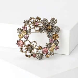 Detail of vintage flower wreath brooch with multi-colored crystals on golden alloy base
