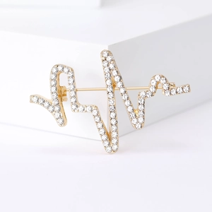 Vue détaillée de la broche rythme cardiaque dorée avec strass et épingle au dos