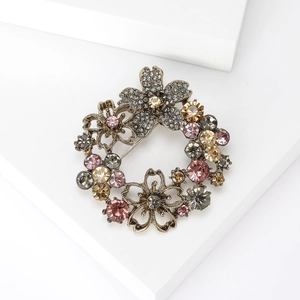 Macro detail of vintage floral wreath brooch with colorful rhinestones on a white stand