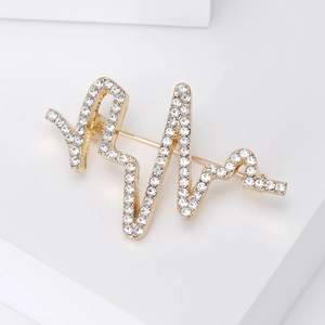 Vue détaillée de la broche battement de coeur dorée avec strass sur socle blanc