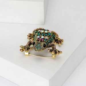 Vintage Froschbrosche in Gold mit bunten Strasssteinen auf minimalistischem Hintergrund