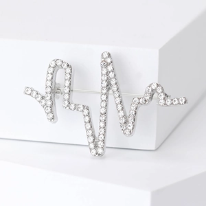 Détail macro d'une broche battement de coeur en argent avec strass et épingle au dos