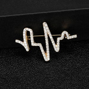Vue macro d'une broche battement de cœur dorée avec strass sur socle noir chic