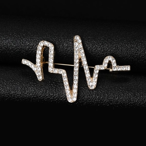 Gros plan d'une broche battement de cœur dorée avec strass blancs sur cuir noir