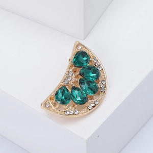 Détail macro d'une broche pastèque avec cristaux verts et monture en alliage doré