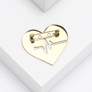 Macro shot of gold heart-shaped brooch with electrocardiogram hollow pattern detail