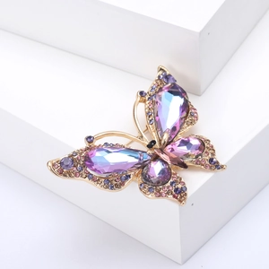 Detail einer eleganten Schmetterlingsbrosche mit lila und blauen Kristallen auf Gold