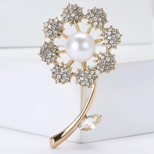 Elegant gold flower brooch with white pearl center and crystal petals on white background