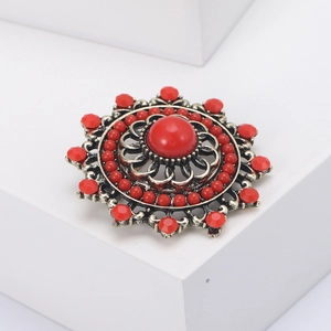 Detailed macro view of bohemian vintage brooch with red beads and antique bronze hollow pattern