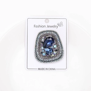 Detailed macro of vintage geometric brooch with blue crystal drop and multi-color rhinestones