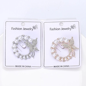 Detailed view of silver and gold wreath brooches with pearls, rhinestones and butterfly