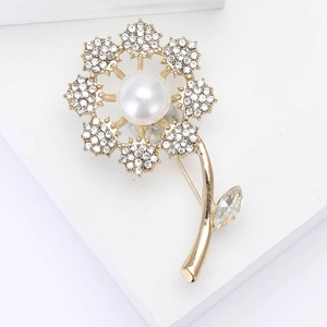 Detail view of dandelion flower brooch with white pearl center and sparkling rhinestones