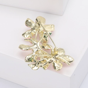 Detail view of the secure safety pin closure and golden metallic back of the peach blossom brooch