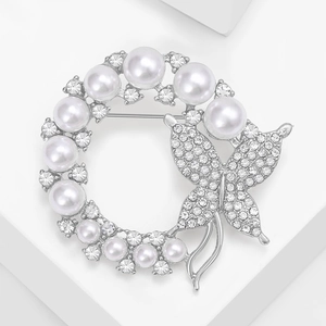 Detailed macro view of silver wreath brooch with pearls, rhinestones and butterfly detail