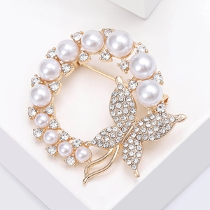 Detail of a gold butterfly and pearl wreath brooch with sparkling rhinestones decoration