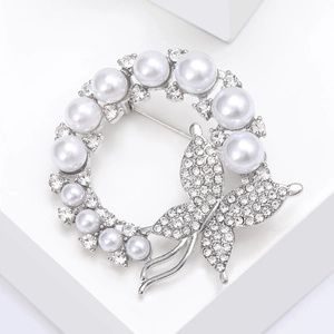 Detailed close-up of a silver wreath brooch featuring pearls and a sparkling butterfly