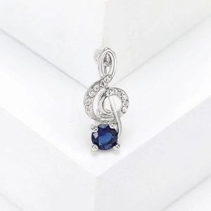 Makroaufnahme von Violinschlüssel-Anhänger mit kleinen Diamanten und blauem Edelstein