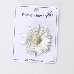 Détail macro de broche marguerite argentée au centre doré sur carte bijou