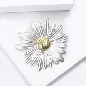 Élégante broche fleur marguerite avec pétales argentés et centre doré sur bloc blanc