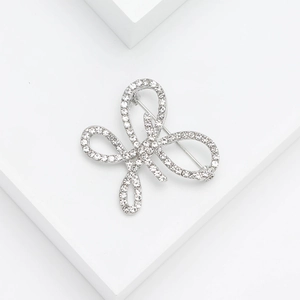 Broche nœud élégante en argent avec strass sur un socle blanc minimaliste