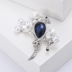 Elegant bird brooch with blue crystal and white pearls on a silver-tone branch