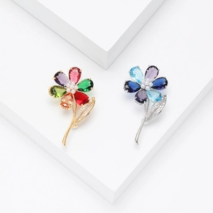 Exquisite flower brooches with multi-colored cubic zirconia and pearls on a white podium