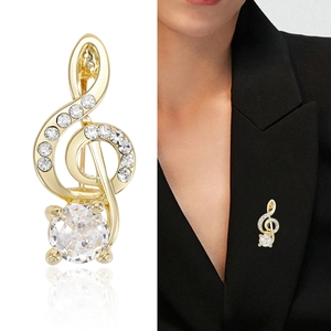 Eleganter goldener Notenschlüssel-Brosche mit Kristallen an einem schwarzen Blazer