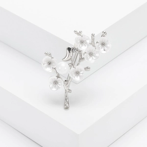 Élégante broche oiseau argentée avec pétales de fleurs et perle sur fond blanc