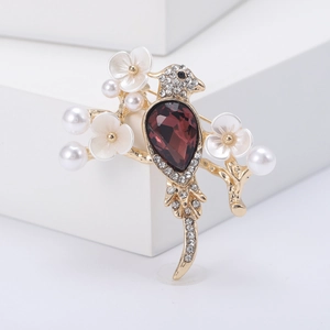 Golden bird brooch with purple teardrop gemstone and sparkling rhinestones on branches