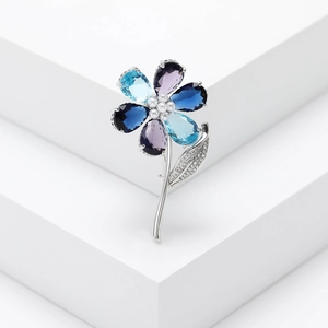 Close-up of elegant floral brooch with blue gems, white pearls and sparkling zircons