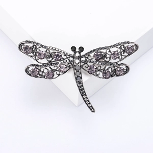 Macro detail of the silver hollow dragonfly brooch with sparkling purple rhinestones