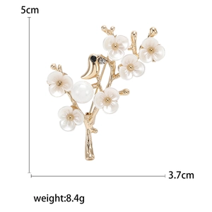 Broche élégante oiseau sur branche de prunier avec fleurs en nacre et une grande perle