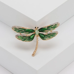 Gros plan détaillé d'une broche libellule avec émail vert et cristaux blancs