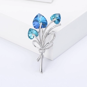 Macro detail of bouquet brooch with blue heart crystals and micro-set zircons on silver metal