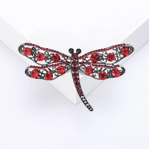 Detail of dragonfly brooch with red rhinestones and silver filigree wing texture