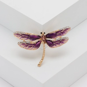 Détail macro d'une broche libellule en émail violet avec pierre de cristal ambre