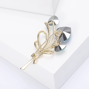Close-up of elegant gold crystal flower bouquet brooch with grey faceted gemstones