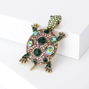 Vue détaillée d'une broche tortue dorée vintage avec strass colorés sur un support blanc pur