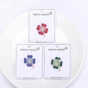 Macro shot of elegant clover brooches with vibrant rhinestones on white display cards
