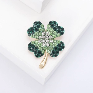 Detailed view of luxury four-leaf clover brooch with green rhinestones on gold base