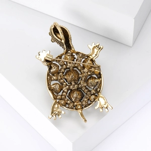 Vue détaillée du dos de la broche tortue dorée montrant l'attache en épingle métal